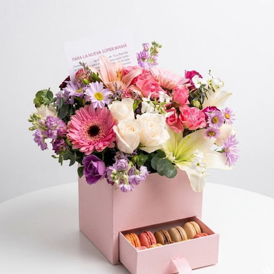 Caja floral con rosas y macarons entregada como regalo para mamá tras el nacimiento de un bebé, en un ambiente cálido y familiar.
